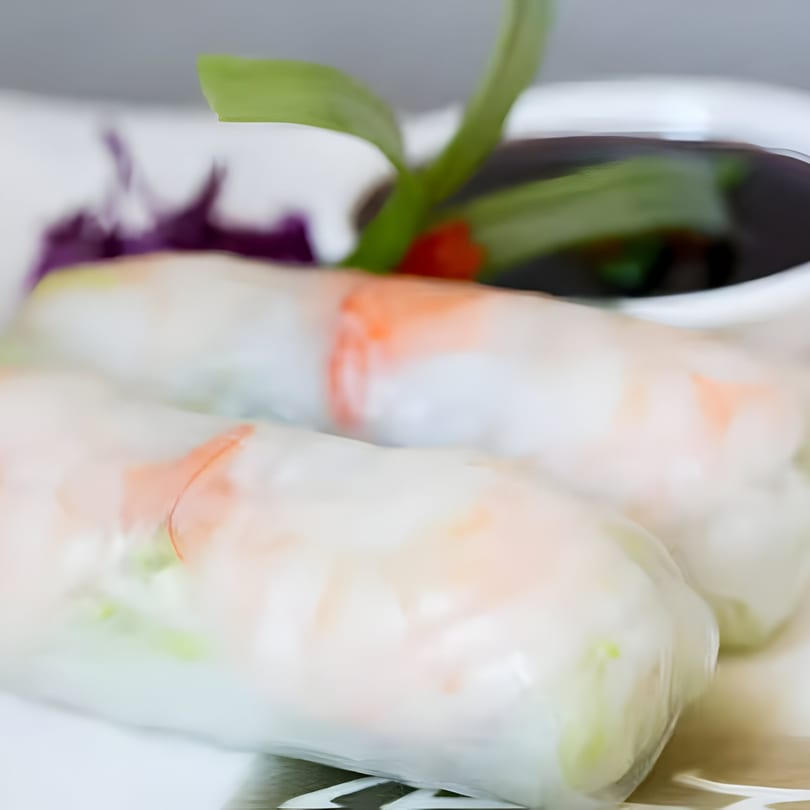 Two fresh Thai spring rolls with shrimp and vegetables, served with a dark dipping sauce.
